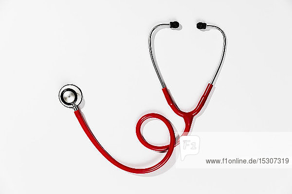 Red stethoscope on white background