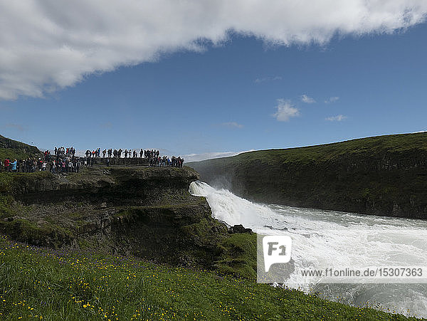Touristen mit Blick auf einen sonnigen  malerischen Wasserfall  Gullfoss  Island