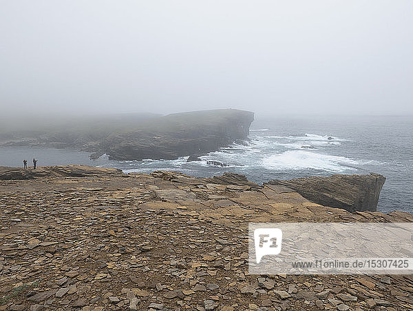 Touristen auf einer zerklüfteten Klippe mit Blick auf das Meer  Orkney-Inseln  Schottland