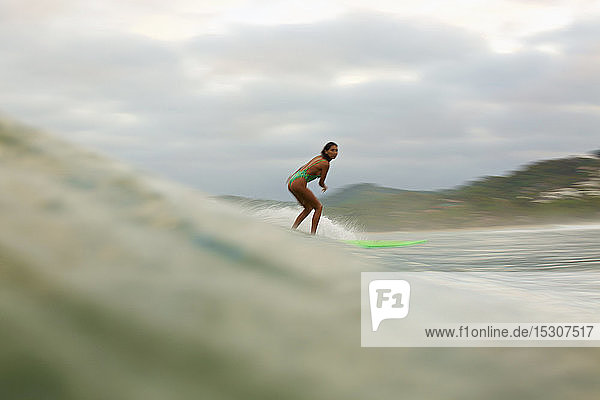 Weibliche Surferin reitet auf einer Meereswelle