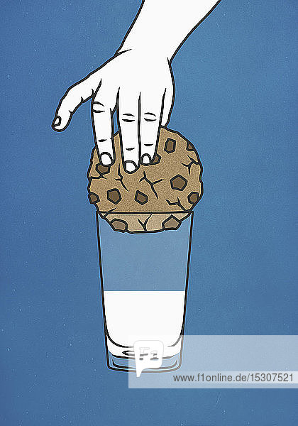 Die Hand versucht  einen großen Keks in ein Glas Milch zu tauchen