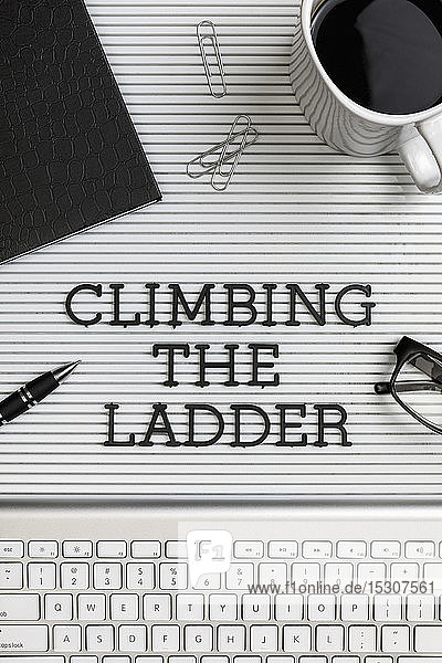 Ansichtsformular über dem Text 'Climbing the Ladder' auf dem Schreibtisch über der Computertastatur