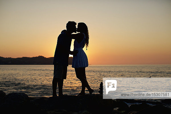 Silhouette junges  romantisches Paar  das sich am idyllischen Strand bei Sonnenuntergang küsst  Sayulita  Nayarit  Mexiko