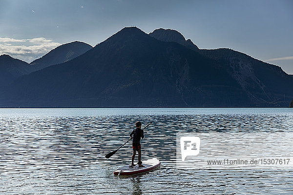 Junge beim Paddeln auf einem sonnigen  idyllischen Bergsee  Walchensee  Bayern  Deutschland