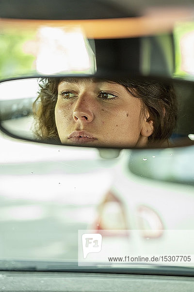 Reflection of woman in rear-view mirror driving car
