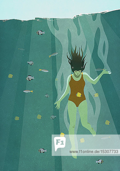 Frau taucht ins Meer  umgeben von Fischen