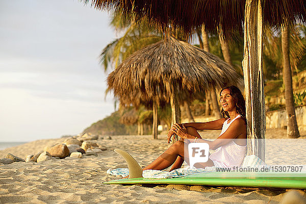 Weibliche Surferin mit Surfbrett entspannt am sonnigen Strand  Sayulita  Nayarit  Mexiko