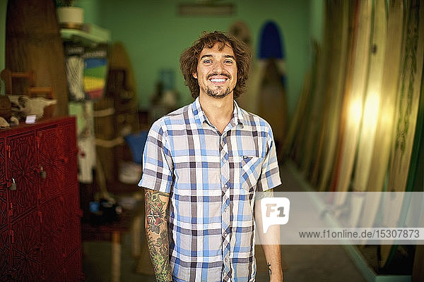 Porträt selbstbewusster  glücklicher männlicher Surfshop-Besitzer