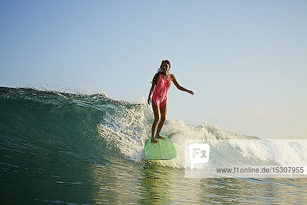Weibliche Surferin reitet auf einer Meereswelle