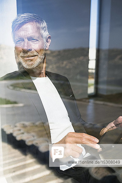 Smiling senior businessman using tablet at the window