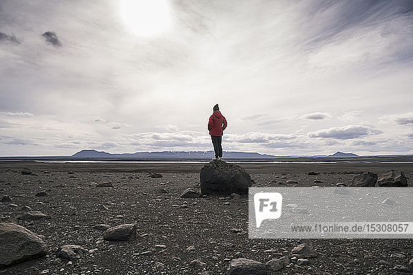 Erwachsener Mann steht auf einem Felsen im vulkanischen Hochland von Island