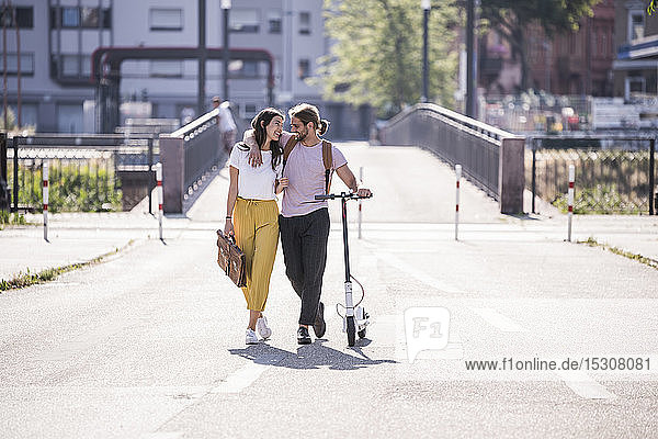 Glückliches junges Paar mit Elektroroller auf der Straße