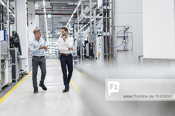 Two businessmen talking in a modern factory