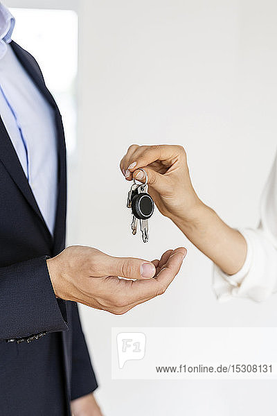 Close-up of real estate agent handing over key to client in new home
