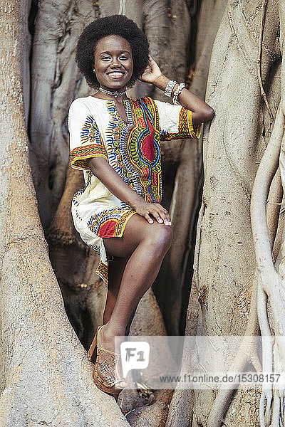Smiling young woman posing in a tree trunk