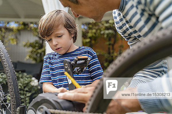 Vater und Sohn reparieren ein Fahrrad im Garten