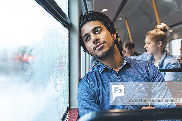 Porträt eines tagträumenden jungen Mannes  der mit dem Bus reist  London  UK