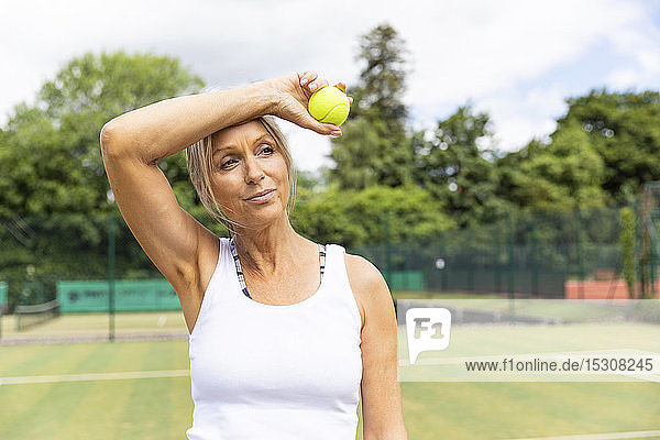 Müde Tennisspielerin macht eine Pause auf dem Rasenplatz des Tennisclubs