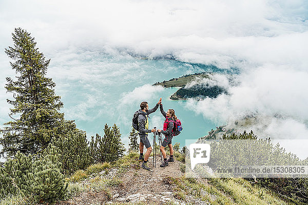 Happy young couple on a hiking trip in the mountains high fiving  Herzogstand  Bavaria  Germany