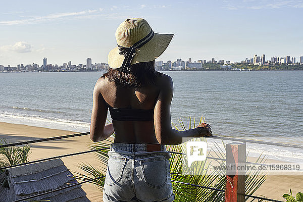Junge Frau am Wasser mit Blick auf die Skyline von Maputo  Mosambik