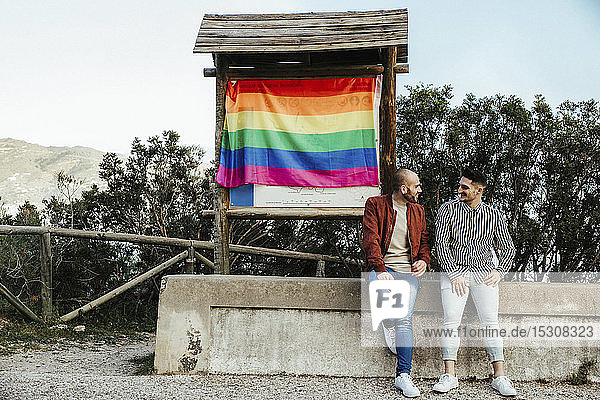 Gay couple with gay pride flag on a trip in the mountains