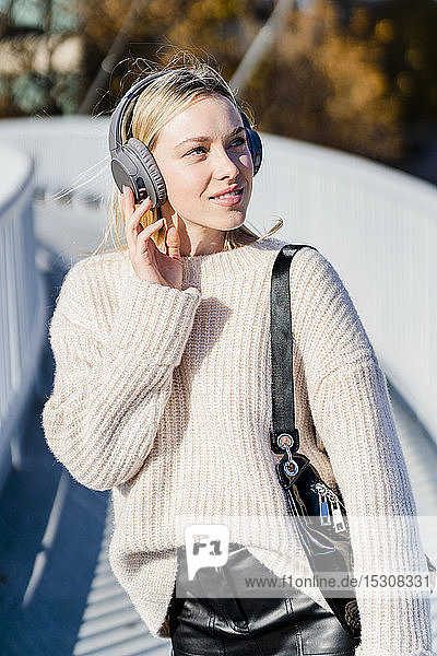 Porträt einer jungen Frau  die im Freien mit Kopfhörern Musik hört