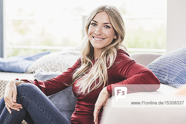 Porträt einer lächelnden blonden Frau  die sich zu Hause entspannt