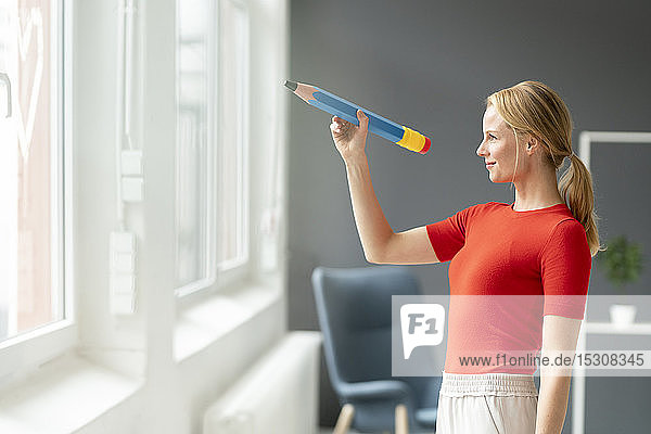 Young woman in office with oversized pen