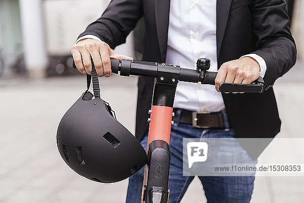 Nahaufnahme eines Geschäftsmannes mit E-Scooter und Helm in der Stadt