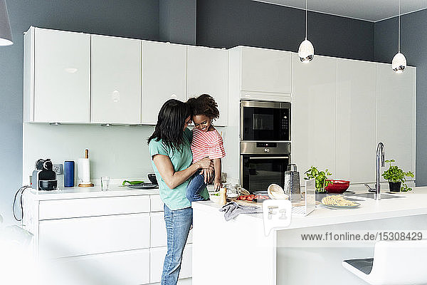 Happy mother holding daughter in kitchen