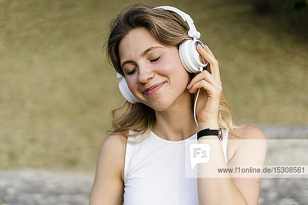 Porträt einer lächelnden jungen Frau  die mit Kopfhörern Musik hört