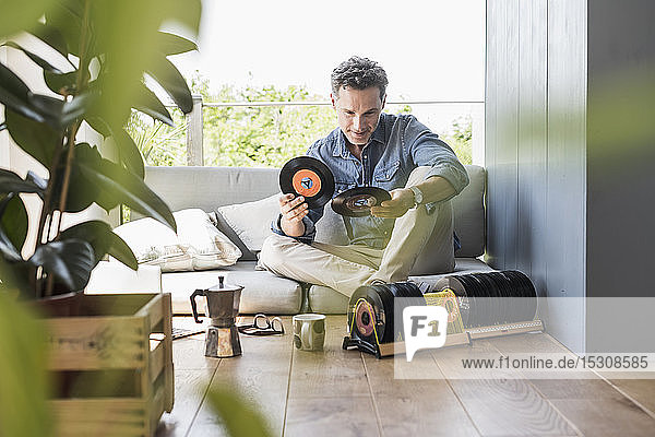 Mature man sitting at home looking at vintage sigle recors