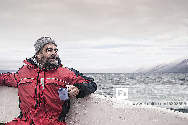 Erwachsener Mann schaut aufs Meer  Bootfahren auf dem Eyjafjordur Fjord  Island