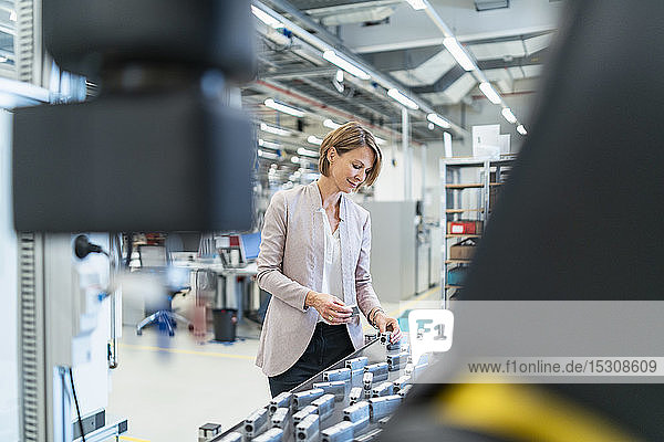 Geschäftsfrau untersucht Werkstücke in einer modernen Fabrikhalle
