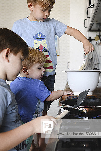 Three brothers cooking pancakes in the kitchen