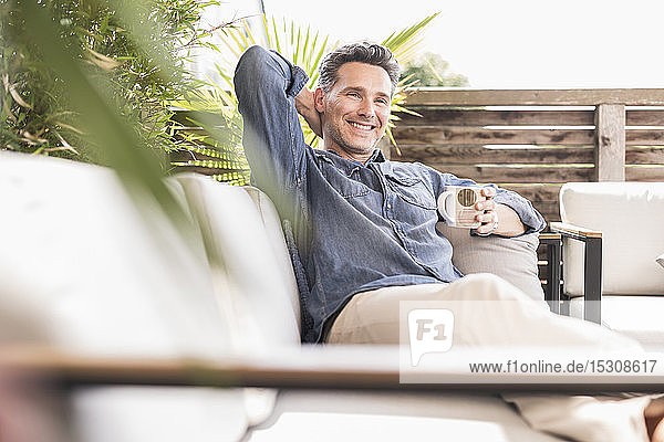 Confident man relaxing on the terrace drinking coffee