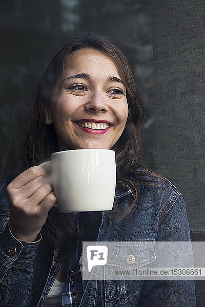 Young woman in cafe with cup of coffee and looking sideways