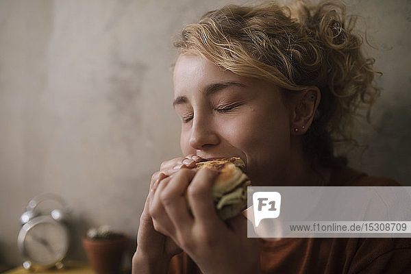 Porträt einer jungen Frau beim Hamburger-Essen