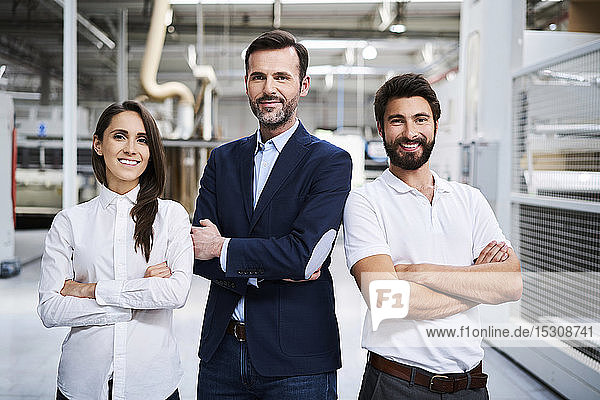 Portrait of confident businessman and employees in a factory