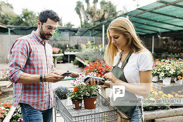Kunde bezahlt mit Smartphone in einem Gartencenter