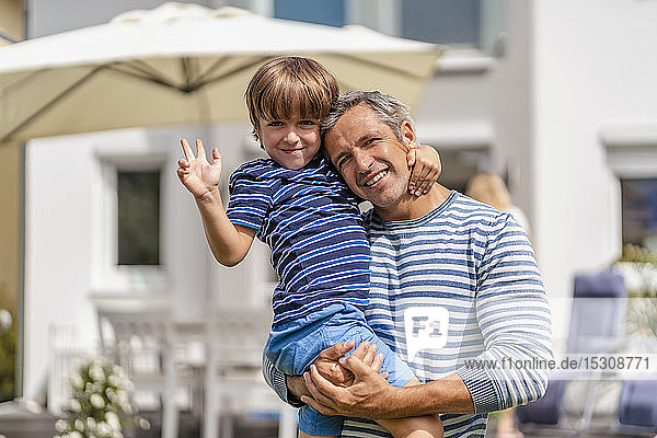 Portrait of father carrying son in garden