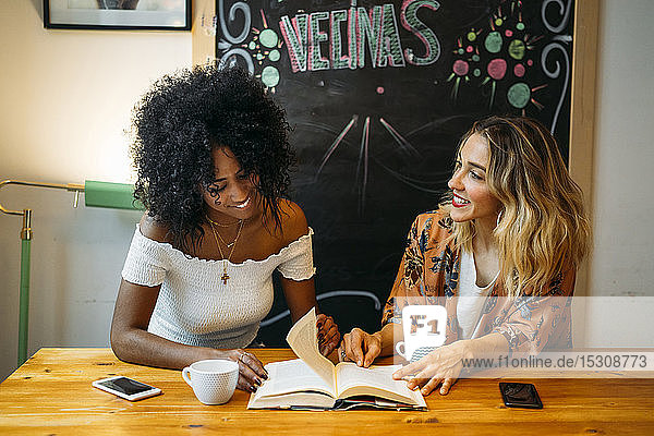 Multikulturelle Frauen unterhalten sich in einem Café  lesen ein Buch