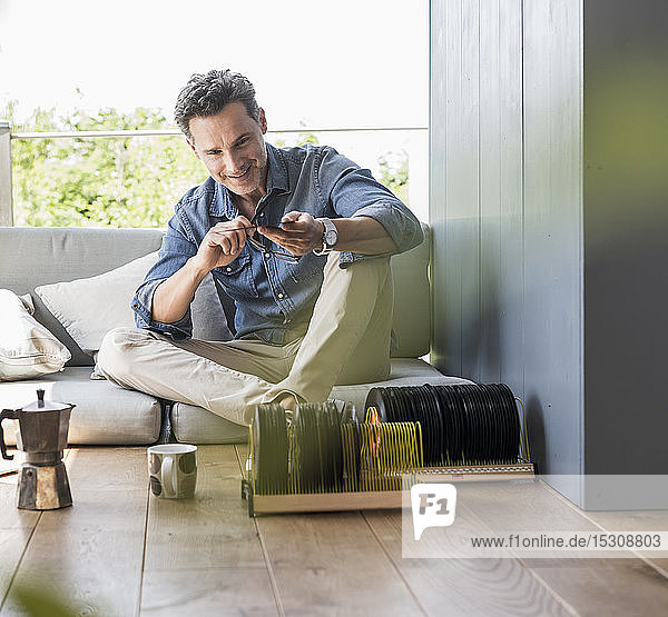 Mature man sitting at home looking at vintage sigle recors