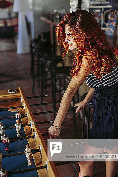 Young woman playing foosball in a sports bar