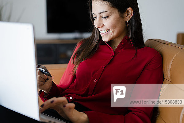Glückliche junge Frau zu Hause beim Online-Shopping