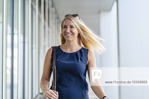 Porträt einer lächelnden blonden Geschäftsfrau in blauem Sommerkleid