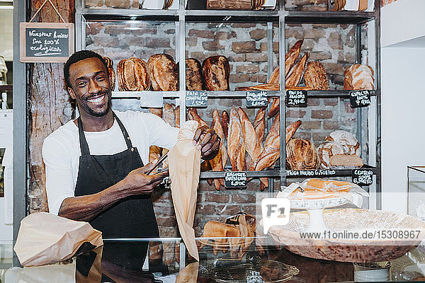 Lächelnder Mann bei der Arbeit in einer Bäckerei