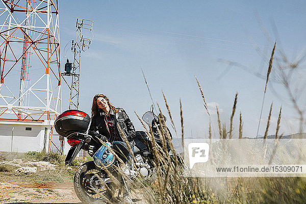 Redheaded woman with motorbike in nature