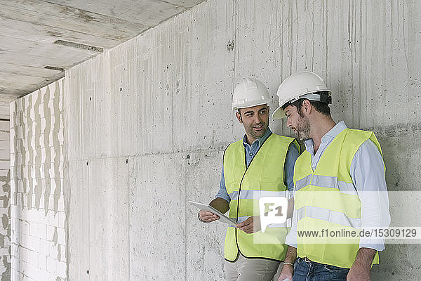 Zwei Arbeiter mit Tablette auf der Baustelle