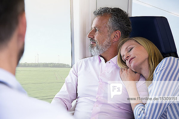 Paar reist mit dem Zug  die Frau stützt sich auf die Schulter des Mannes